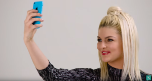 Stylight model met blond haar in grafische jurk maakt selfie